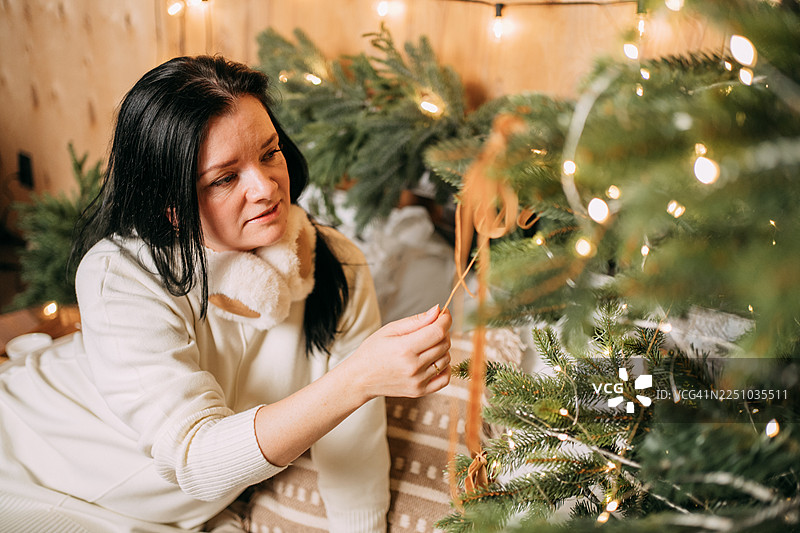 一位女士在家中为节日装饰圣诞树图片素材