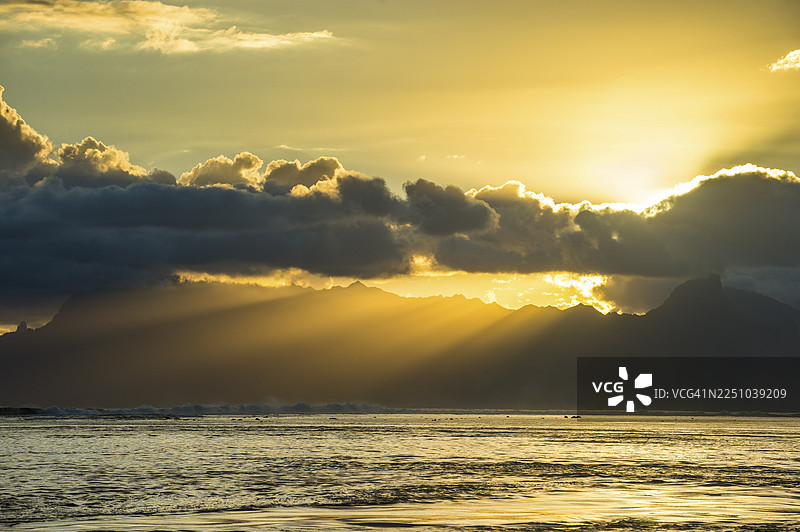 阳光穿透莫雷阿岛、帕佩特、塔希提岛上空的云层图片素材