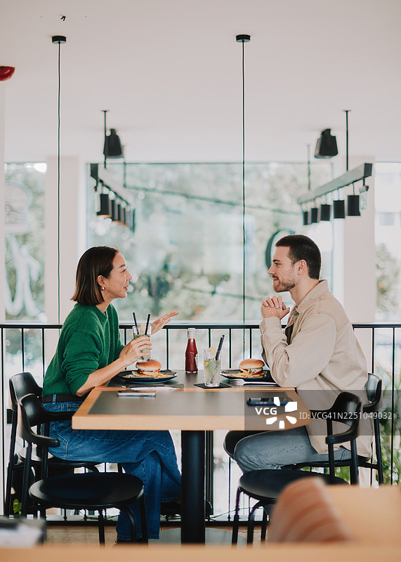 年轻情侣在现代餐厅享受休闲约会，分享食物并愉快交谈图片素材