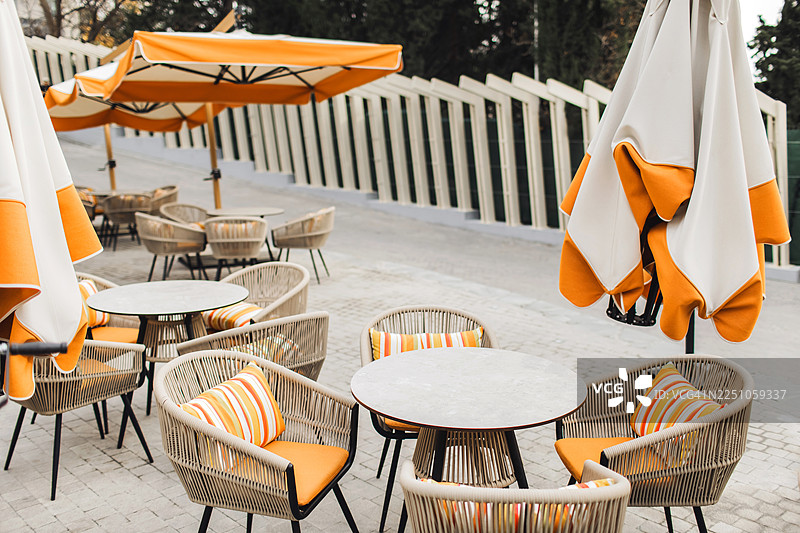 淡季欧洲户外咖啡馆，配有橙色坐垫和遮阳伞图片素材