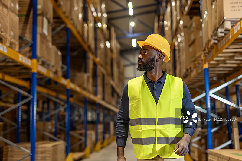 穿着安全装备的仓库工作人员正在管理货架和库存图片素材