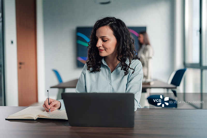 女商人正在办公室用笔记本电脑写下想法图片素材