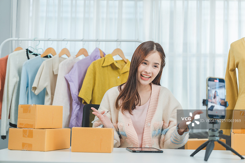 年轻女子在家中直播时尚内容，展示潮流服饰。网络红人轻松提升观众互动和销量。图片素材