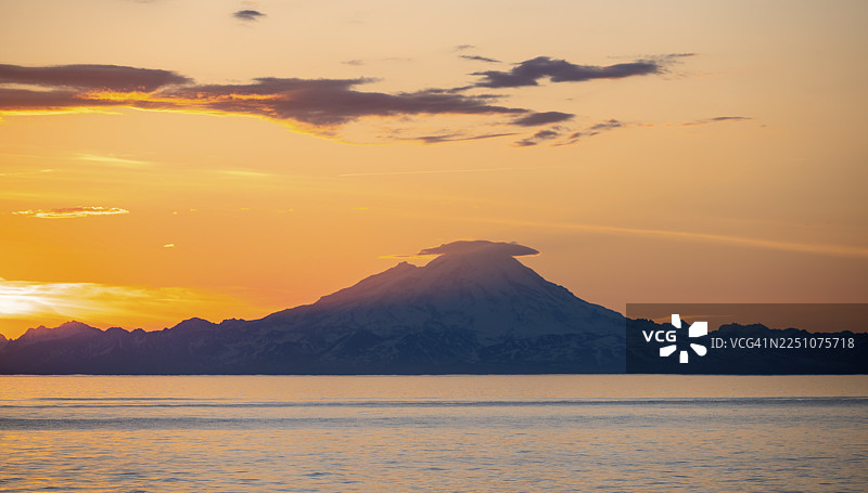 日落时分，红山 (Mount Redoubt) 白雪皑皑的山峰映衬着库克湾 (Cook Inlet) 的景色，午夜阳光洒下如画般的金色光芒，远眺阿留申山脉 (Aleutian Range)，这里是美国的安克雷奇角 (Anchor Point) 和安克雷奇河州立休闲区 (Anchor River State Recreation Area)。图片素材