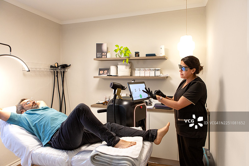 皮肤科医生为男性患者进行激光治疗，对抗灰指甲图片素材