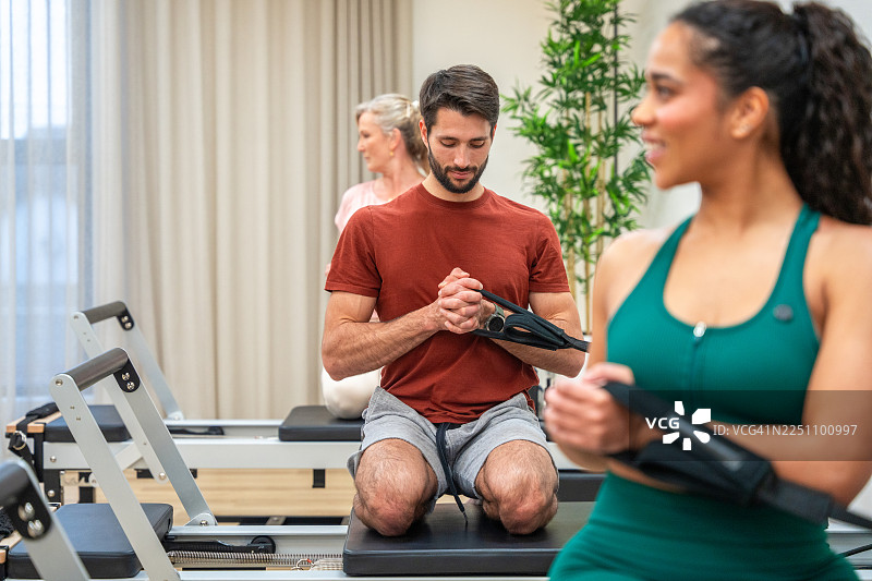 年轻白人男性在集体环境中练习普拉提改革器图片素材