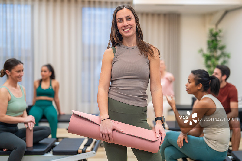 年轻的高加索女性运动员在普拉提课上拿着瑜伽垫图片素材