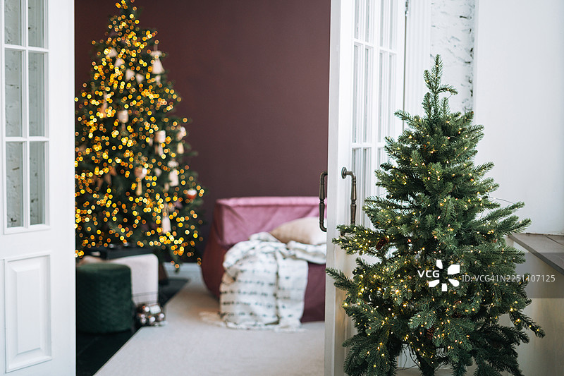 舒适现代室内装饰着白色饰品和闪烁灯光的节日圣诞树。节日概念图片素材