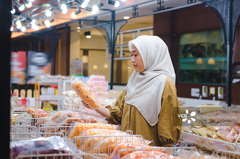 亚洲穆斯林女性在现代市场购买当地小吃图片素材