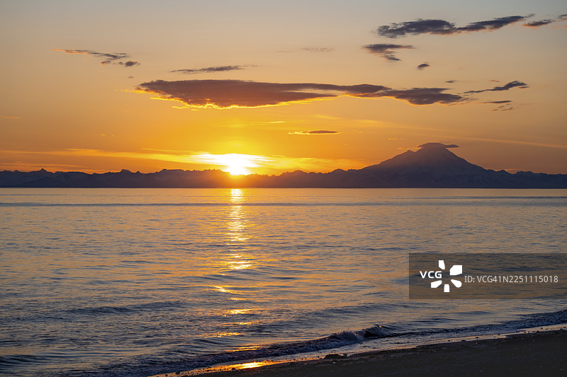 日落时分,红山(Mount Redoubt)白雪皑皑的山峰映衬着库克湾(Cook Inlet)的景色,午夜阳光投下如画般的金色光芒,远眺阿留申山脉(Aleutian Range)、锚点(Anchor Point)、锚河州立休闲区(Anchor River State Recreation Area),位于美国阿拉斯加州。图片素材
