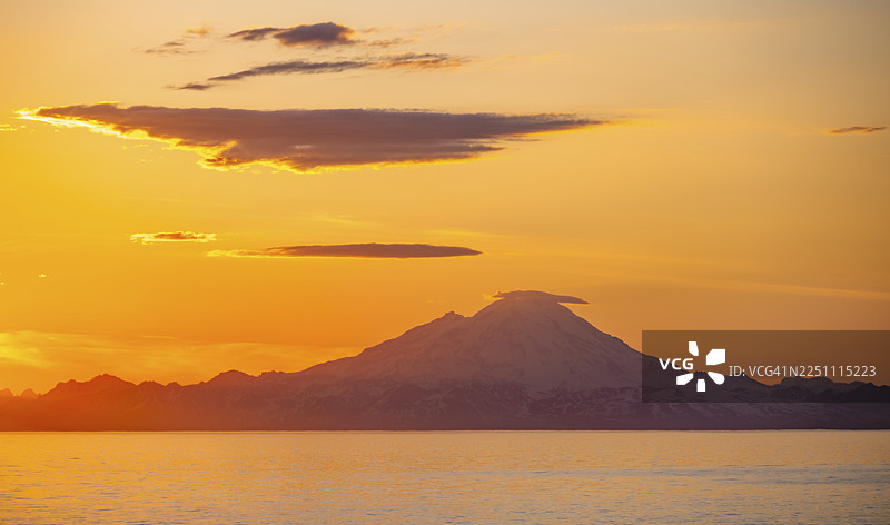 日落时分,红山(Mount Redoubt)白雪皑皑的山峰映衬着库克湾(Cook Inlet)的景色,午夜阳光投下风景如画的金色光芒,阿留申山脉(Aleutian Range)、锚点(Anchor Point)、锚河州立娱乐区(Anchor River State Recreation Area)、阿拉斯加、美国。图片素材