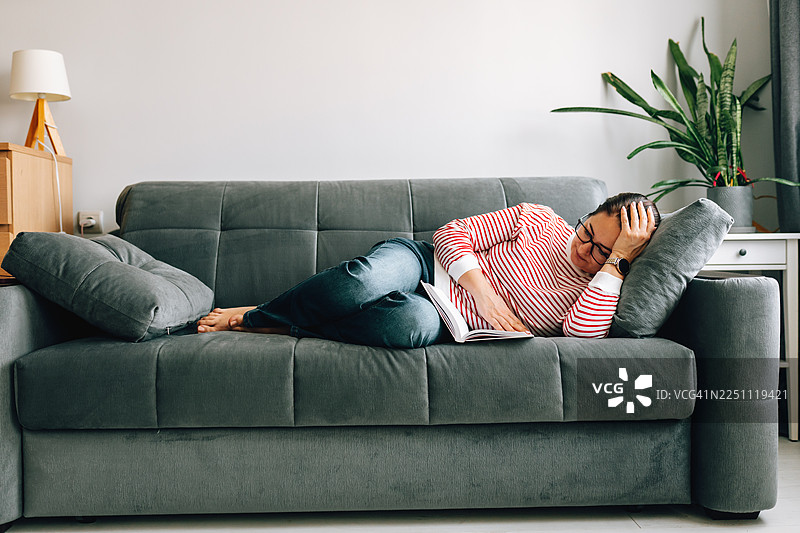 女子在家中沙发上随意地看书休息图片素材
