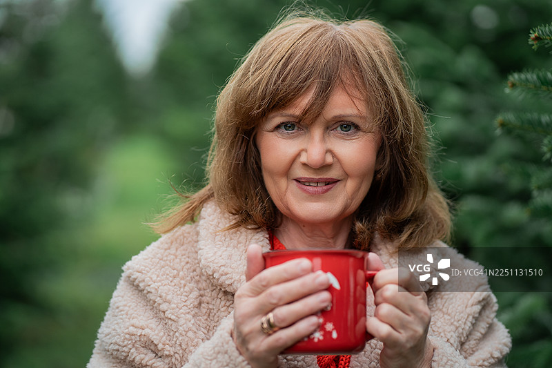 一位55岁的女士在户外市场挑选圣诞树。冬季节日。图片素材