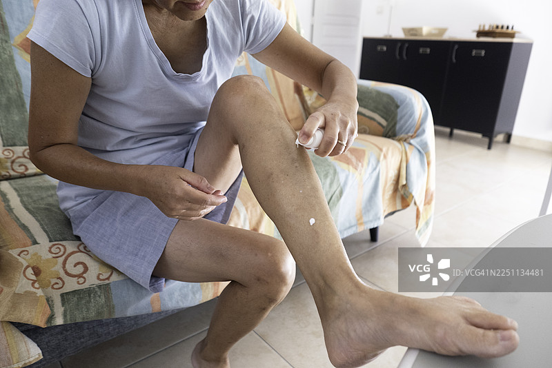 女子将化妆品乳液倒在腿上图片素材