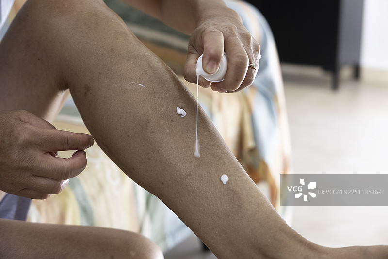 女子将化妆品乳液倒在腿上图片素材