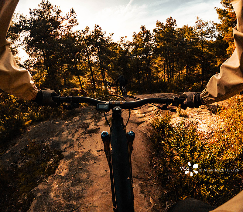 第一人称视角，朋友们在布满岩石的林间小径上骑山地自行车下行图片素材