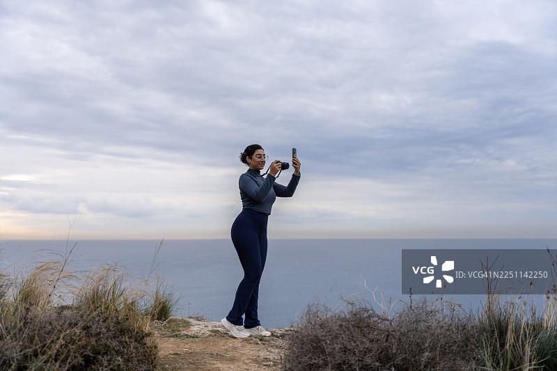 一位微笑的女摄影师在海边拍照图片素材