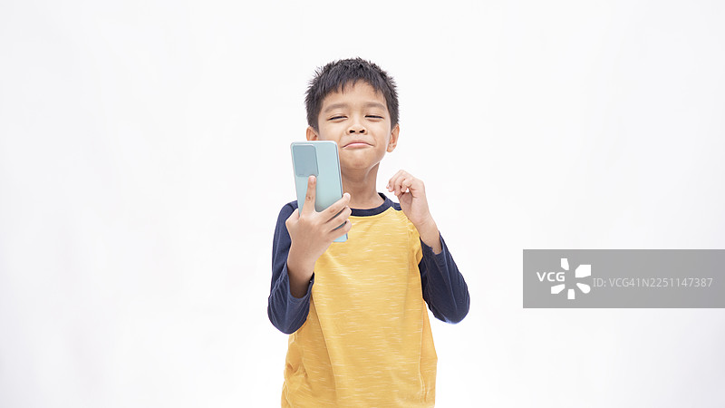亚洲小男孩对着手机里的视频大笑，背景是白色图片素材