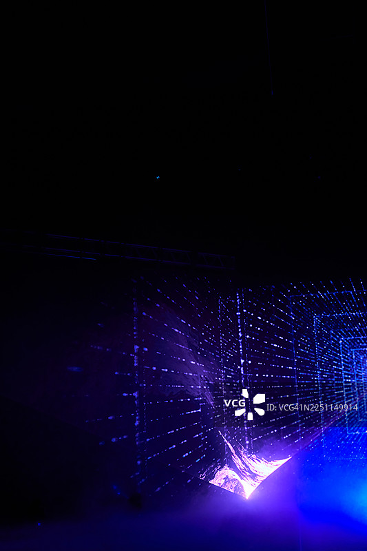 黑暗场景中，带有发光光束和数字粒子的未来感紫色激光网格隧道图片素材