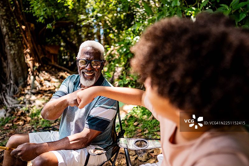 爷爷和孙子在湖边钓鱼时击掌图片素材