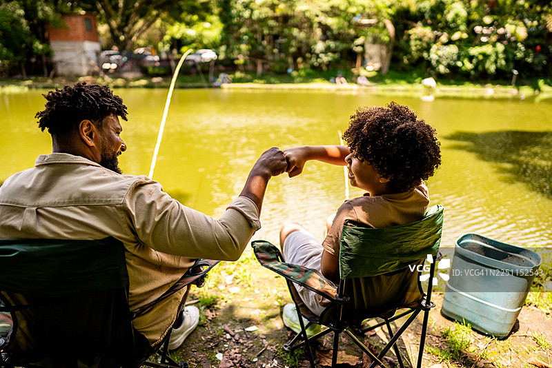 父亲和儿子在湖边钓鱼时击掌图片素材