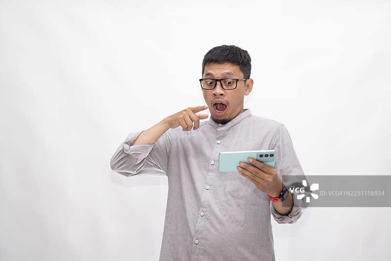 亚洲男子震惊地看着智能手机图片素材
