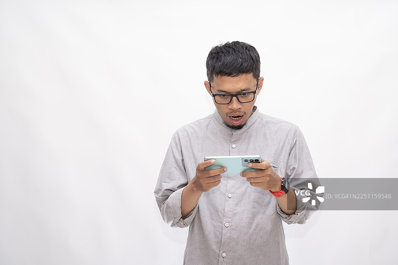 亚洲男性震惊地看着智能手机图片素材