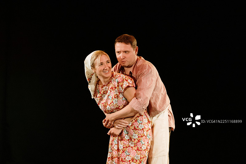 浪漫的戏剧场景：在花卉主题表演中，一对情侣在舞台上拥抱图片素材