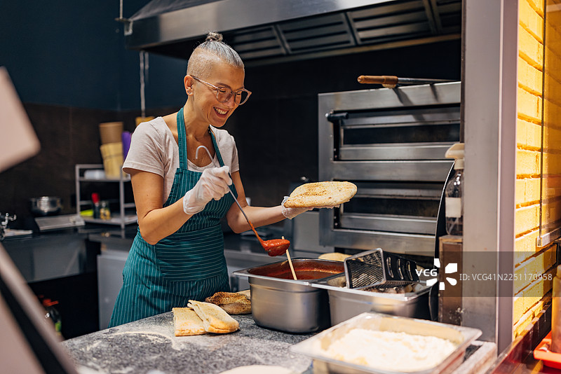 女厨师在专业厨房里制作酿馅的意式炸饺，配番茄酱图片素材