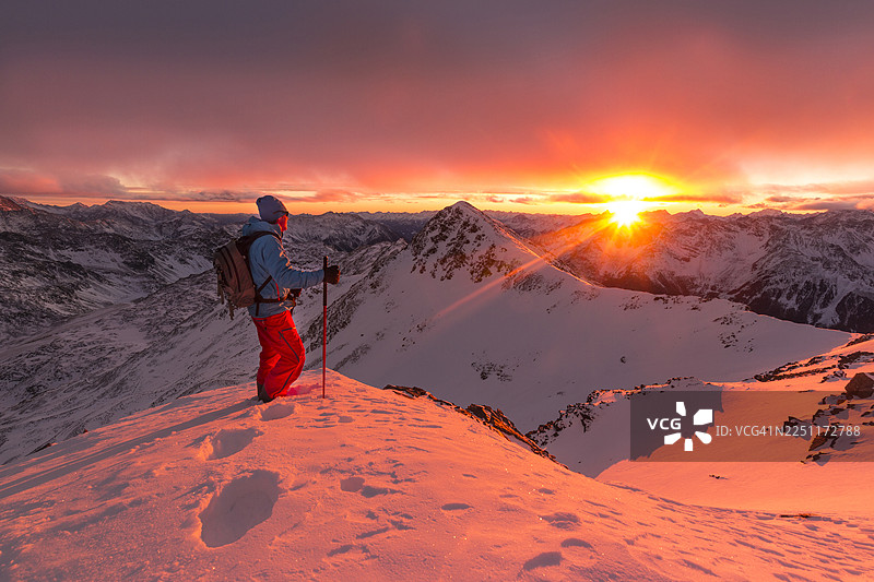 滑雪登山者在日落时分欣赏火红的天空图片素材