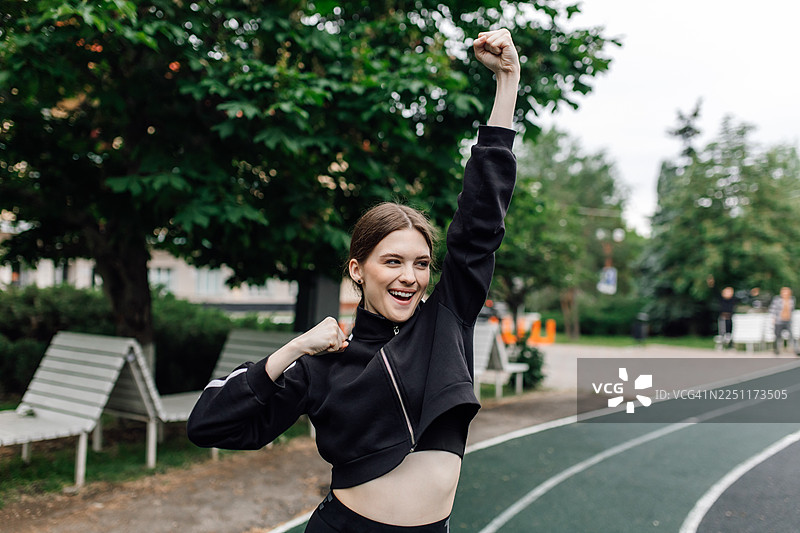年轻女子在跑道上庆祝胜利的欢乐户外瞬间图片素材