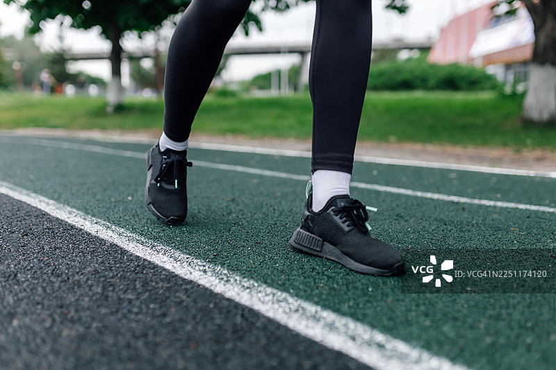 运动员的脚踩在绿色的户外跑道上，准备开始锻炼图片素材