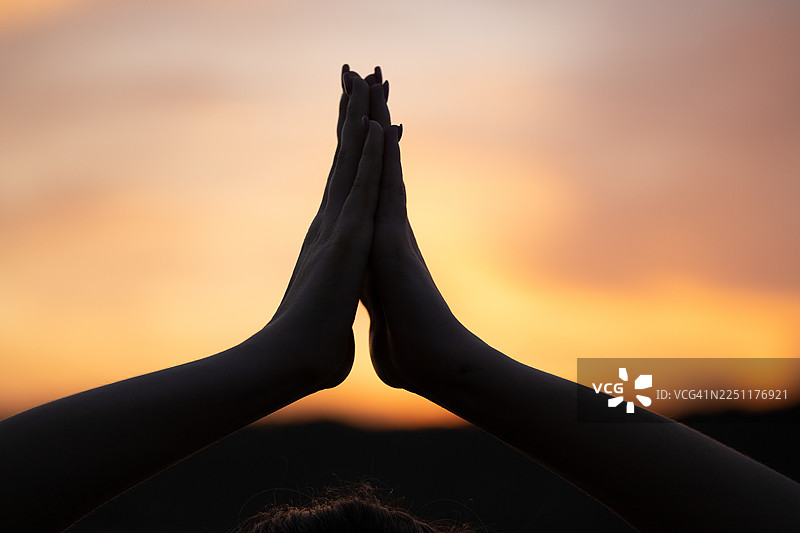夕阳暖意映衬下，双手合十祈祷的剪影，宁静的反思时刻图片素材