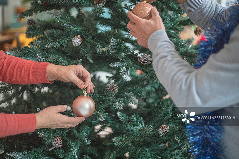 人类的手正在给圣诞树装饰圣诞装饰品图片素材