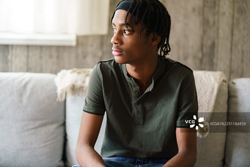 一个留着脏辫的年轻黑人男子在家中沉思。图片素材