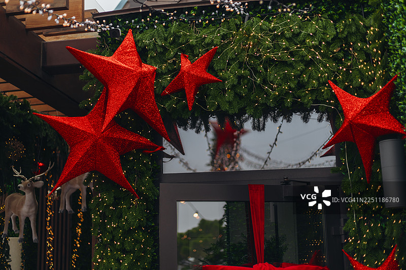 一个圣诞入口，装饰着巨大的闪亮红星、郁郁葱葱的绿花环和闪烁的灯光。图片素材