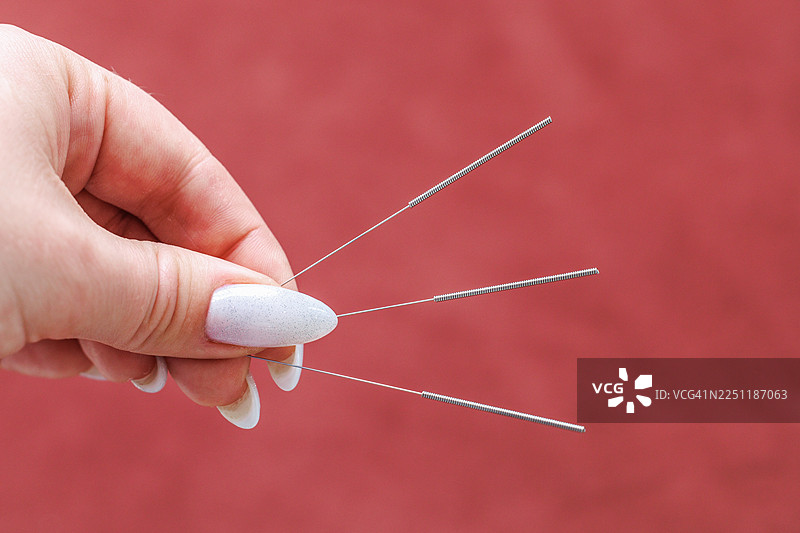 特写一只手，手持用于传统治疗和健康理疗的针灸针图片素材