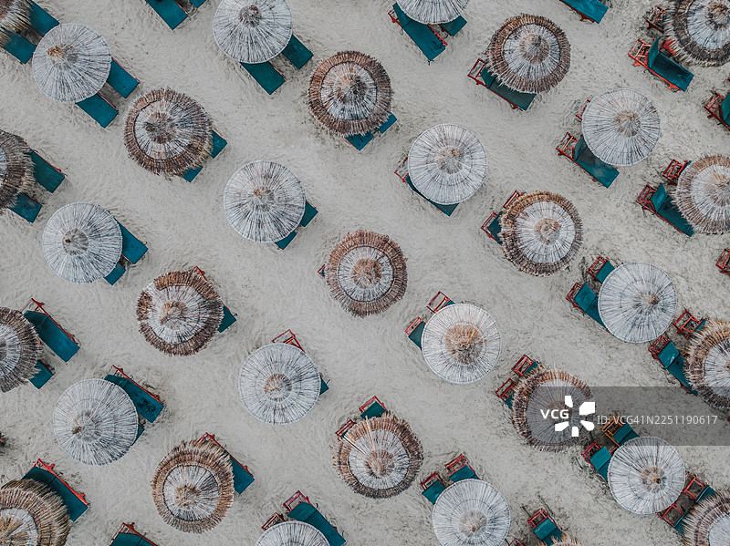 无人机视角拍摄的沙滩上成排的茅草遮阳伞，阿尔巴尼亚都拉斯县都拉斯市图片素材