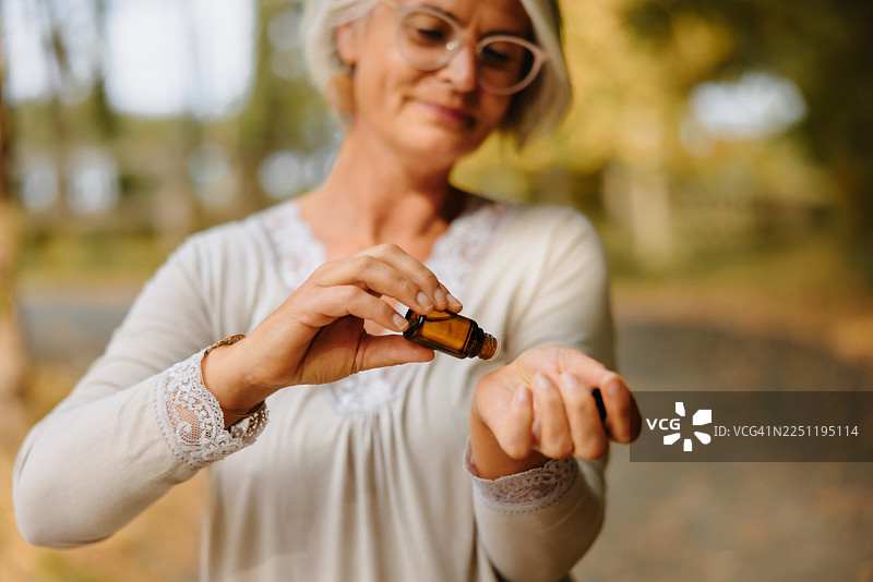 特写镜头：一位成熟的女性在手腕内侧涂抹精油进行芳香疗法图片素材