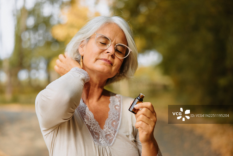 一位成熟的女性将精油从手腕内侧涂抹到耳后图片素材