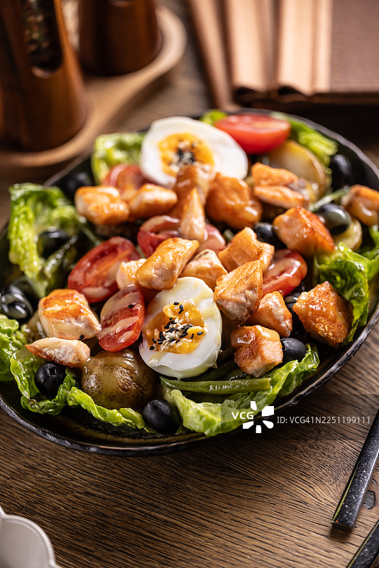 这款尼斯沙拉的变种与传统做法不同，它用香煎三文鱼块代替金枪鱼，放在脆生菜上，配以黑橄榄、青橄榄和对半切的煮鸡蛋。图片素材