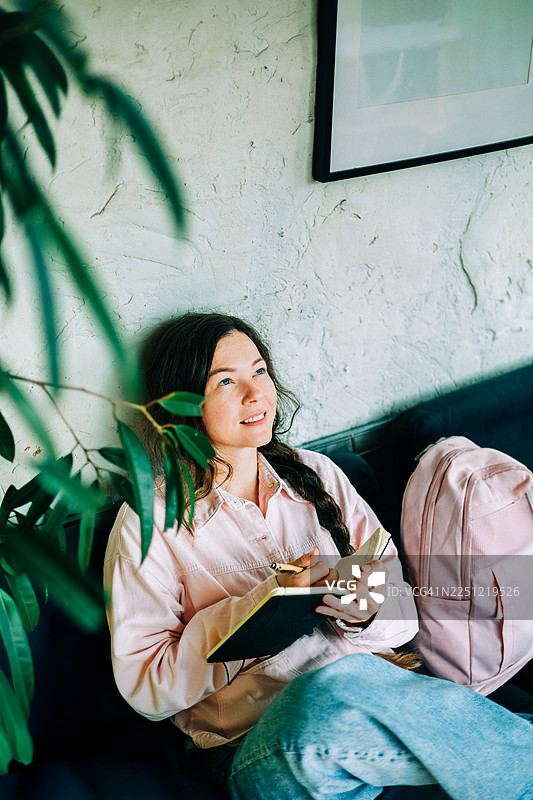 女人在家中，在室内植物旁记录想法和点子图片素材