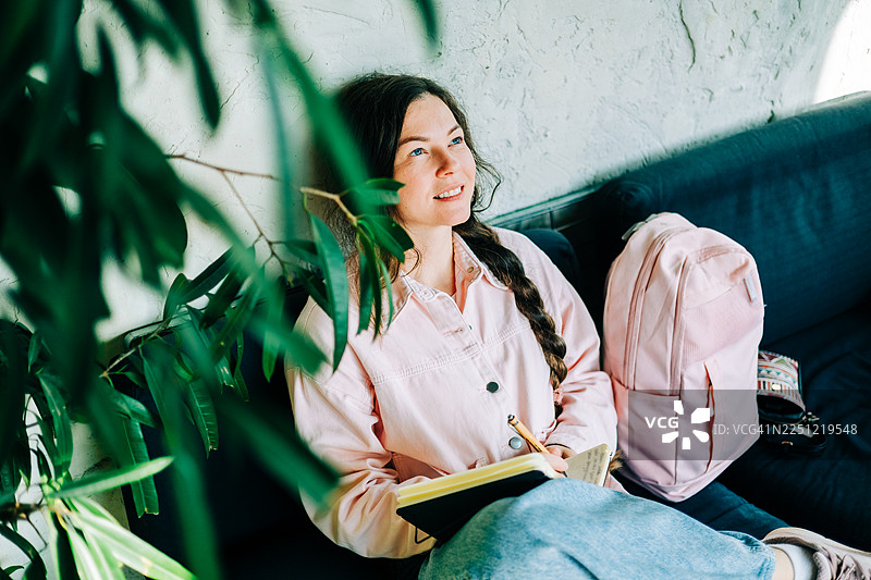 女子在家中，在室内植物旁记录想法和灵感图片素材