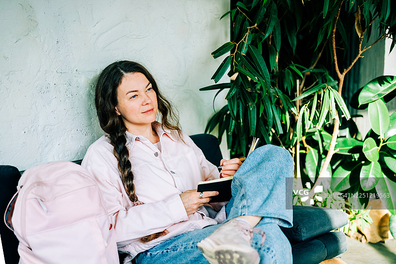 女人在沙发上写日记并思考创意图片素材