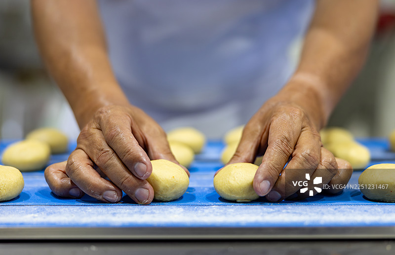 面包师在工业化面包房工作，揉捏面团图片素材