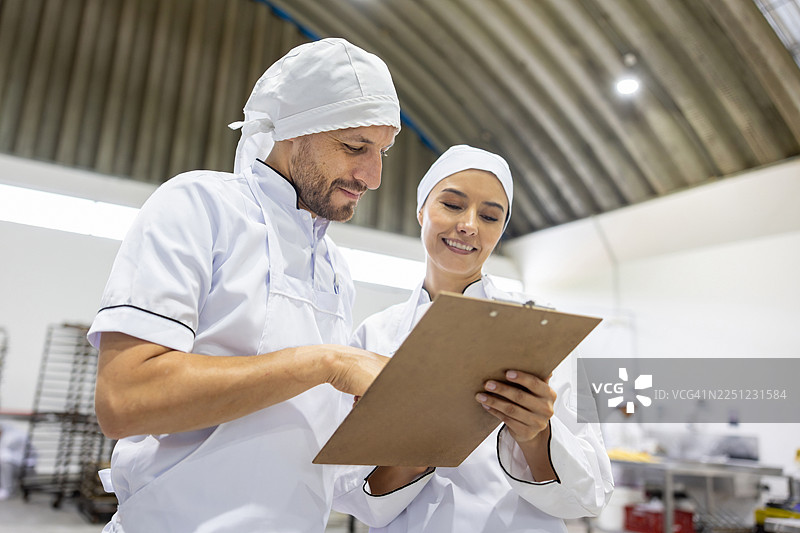 经理向在面包店工作的员工展示日程表图片素材