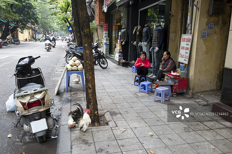 两位女士坐在河内市中心的商店前图片素材