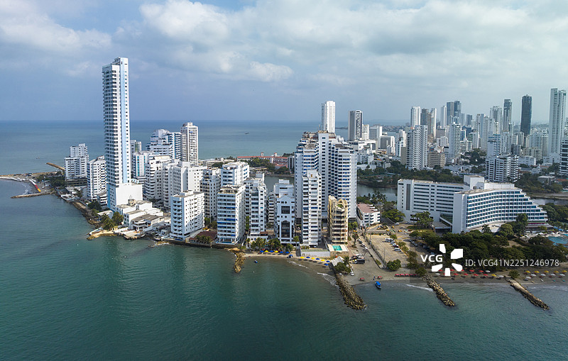 哥伦比亚卡塔赫纳的海滨天际线，现代高层建筑环绕着蔚蓝的海洋和多云的天空。图片素材