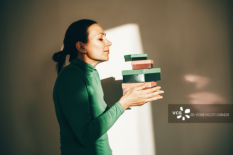 身穿绿色高领衫的女子在温暖的阳光下于工作室中平衡彩色积木图片素材