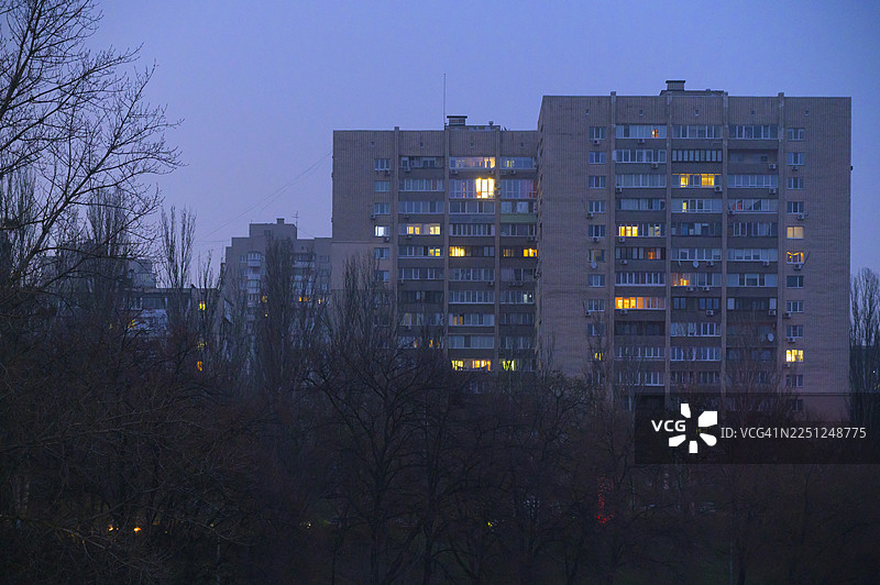 黄昏时分，高耸的公寓楼，窗户灯火通明图片素材